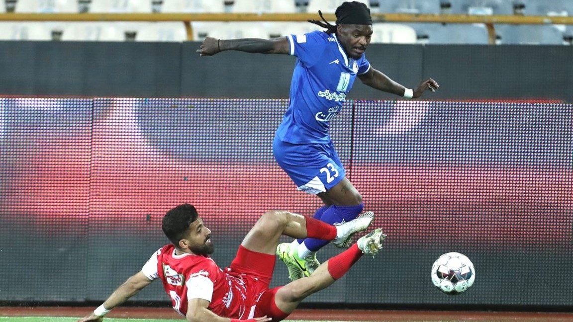 تیوی بیفوما مهاجم استقلال خوزستان در حال دریبل فرشاد فرجی مدافع پرسپولیس